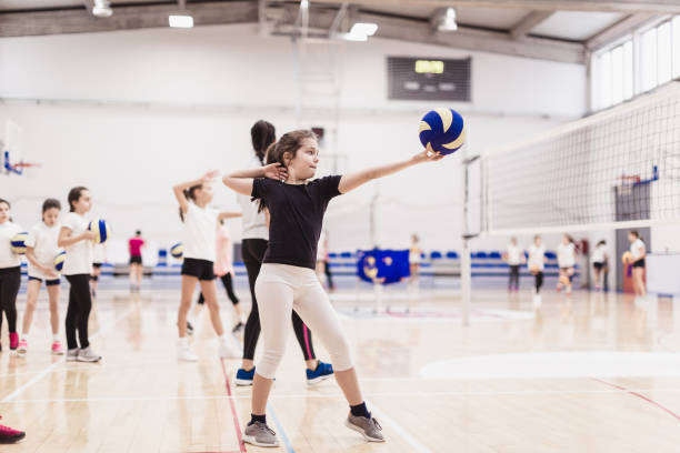 Female volleyball team exercising indoors Female volleyball having training on volleyball court young volleyball girl stock pictures, royalty-free photos & images