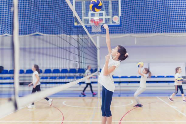 Female volleyball team exercising indoors Female volleyball having training on volleyball court young volleyball girl stock pictures, royalty-free photos & images