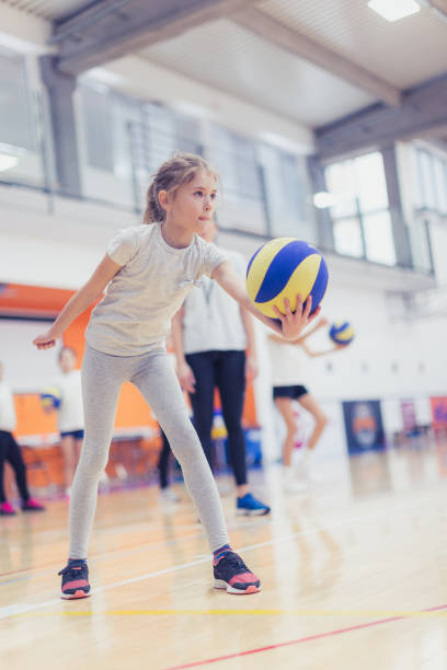 Female volleyball team exercising indoors Female volleyball having training on volleyball court young volleyball girl stock pictures, royalty-free photos & images