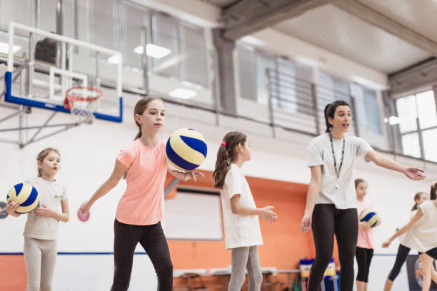 Female coach talking with girls at volleyball court Female coach talking with girls at volleyball court. She teaching them how to play better young volleyball girl stock pictures, royalty-free photos & images
