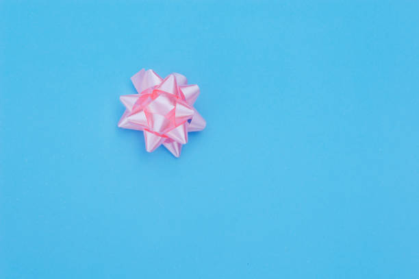 istock pink bow on a blue background, space for your text, a template for invitation, brochures, banners 1129380132