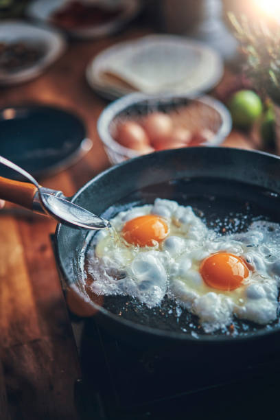 Frying Egg in a Cooking Pan in Domestic Kitchen stock photo