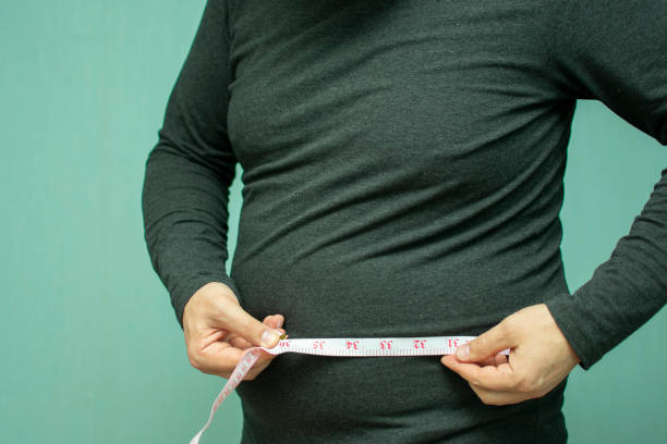 full man with belly measures the volume of his waist - loose weight imagens e fotografias de stock