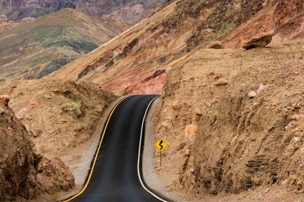 Road leading over hill at Death Valley National Park Road through Artists Drive in Death Valley National Park, California, USA that leads over a hill and seems to disappear in the mountains bumpy photos stock pictures, royalty-free photos & images