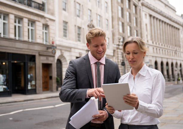 istock Couple of business people working online outdoors on a tablet computer 1129386326
