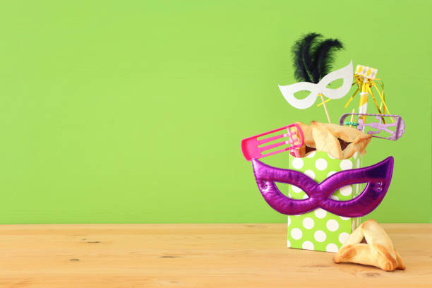 istock Purim celebration concept (jewish carnival holiday) over wooden table and purple background. 1129386835