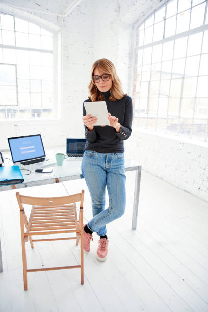 istock Businesswoman using digital tablet while standing in the office 1129387873