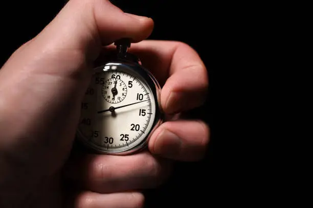 Male hand take analog stopwatch on a black background, close-up, isolate, copy space
