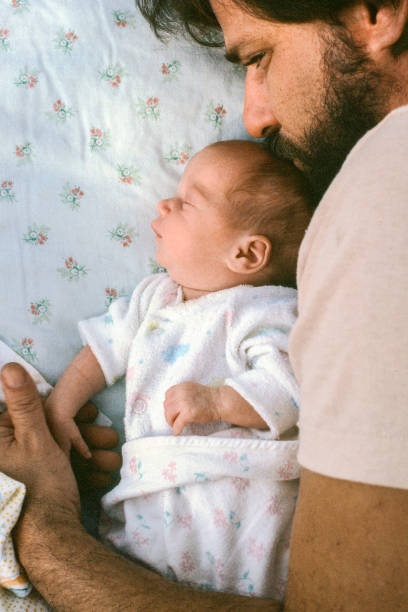 Father and newborn daughter A vertical image of a father with his arm curled around his newborn daughter. The photo is shot from top down. It is cropped tight with room for type. The image conjures up images of love, trust, security, and the future father daughter 80s stock pictures, royalty-free photos & images