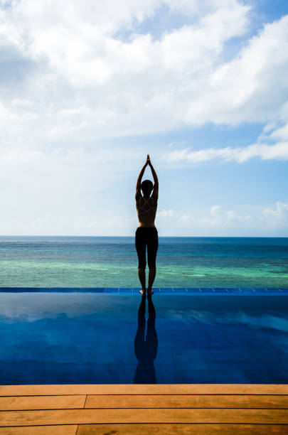 istock Young woman practicing yoga on the Infinity pool 1129391187