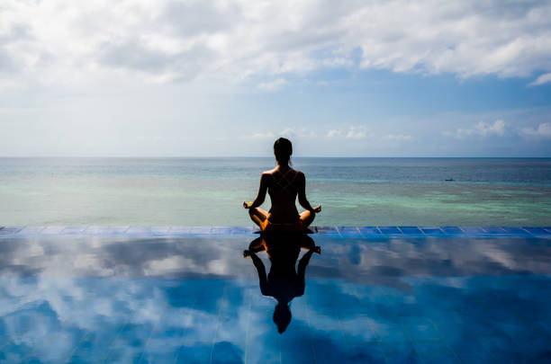 Young woman practicing yoga lotus position on the Infinity pool Mindfulness, Tranquility, Idyllic, Relaxation, Beauty, Lifestyles, Body Conscious, spiritual enlightenment stock pictures, royalty-free photos & images