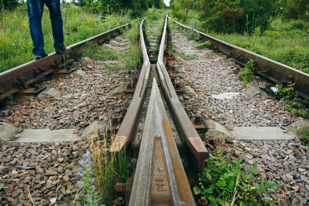 istock Man is standing on old rusty railway lines with grey stone chippings. Natural industrial background texture. 1129397806
