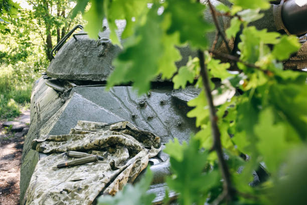istock Shell missile is lying on the old khaki jacket. Historical things on armored fighting vehicle. Rusty dye of tank background texture. 1129398047