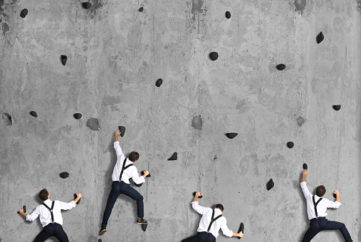 Business concept, a group of employees climbs up on the concrete wall.