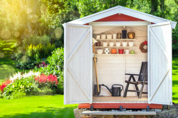 Garden shed filled with gardening tools with green sunny garden in the background. stock photo