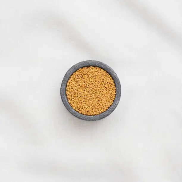 Bee Pollen in a small bowl on a white linen table cloth