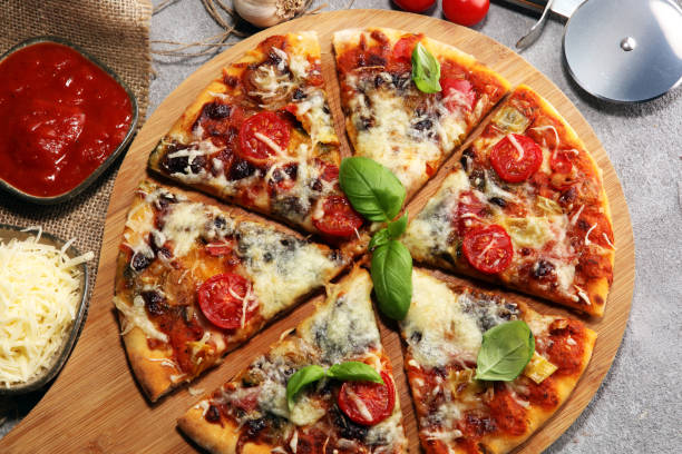 istock Vegetarian Italian pizza with melted cheese, red tomatoes and green basil on a table decorated by cheese, tomato and cherry tomatoes 1129403631