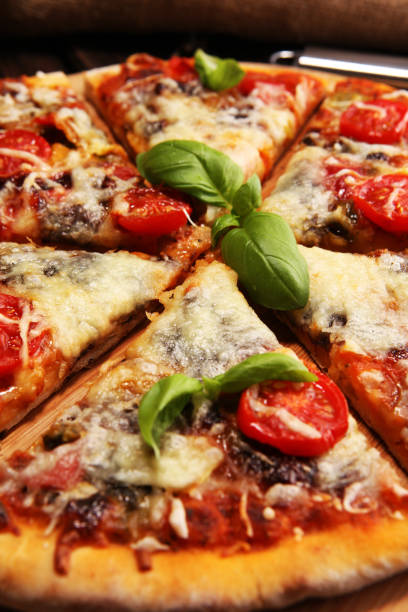 istock Vegetarian Italian pizza with melted cheese, red tomatoes and green basil on a table decorated by cheese, tomato and cherry tomatoes 1129404589