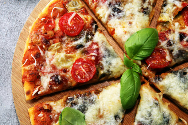 istock Vegetarian Italian pizza with melted cheese, red tomatoes and green basil on a table decorated by cheese, tomato and cherry tomatoes 1129405364