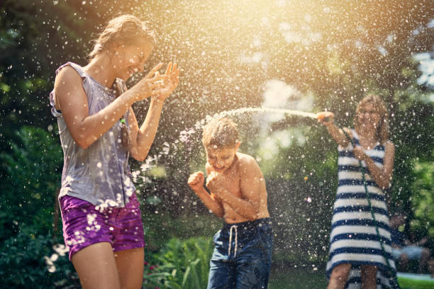 istock Mother splashing laughing kids in back yard 1129406193