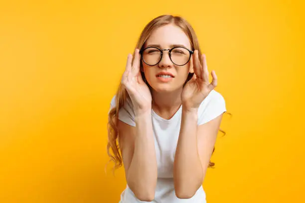 Photo of A girl with poor eyesight wears glasses, looking squinting, trying to figure out what is written on a yellow background