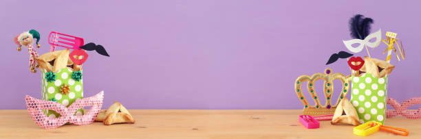 istock Purim celebration concept (jewish carnival holiday) over wooden table and purple background. 1129410046