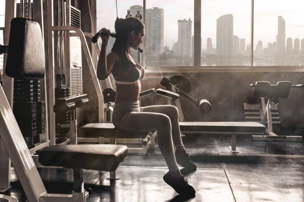 sexy asian women exercising with a lat pulldown machine to play the arms and shoulder muscles in the gym. exercise in the gym concept .dark tone - 2547 imagens e fotografias de stock