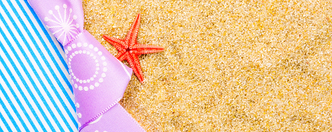 holiday gift card with violet bow and ribbon in the middle and background made of sand and star sea shell with plenty copy space for the text