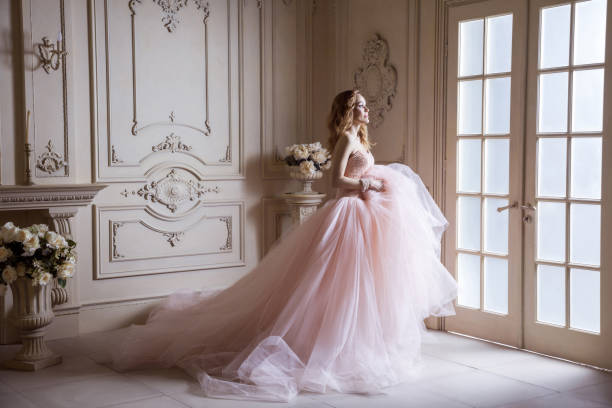 beautiful young blond woman in luxurious long pink dress posing in vintage room interior. - bride wedding fashion evening gown imagens e fotografias de stock