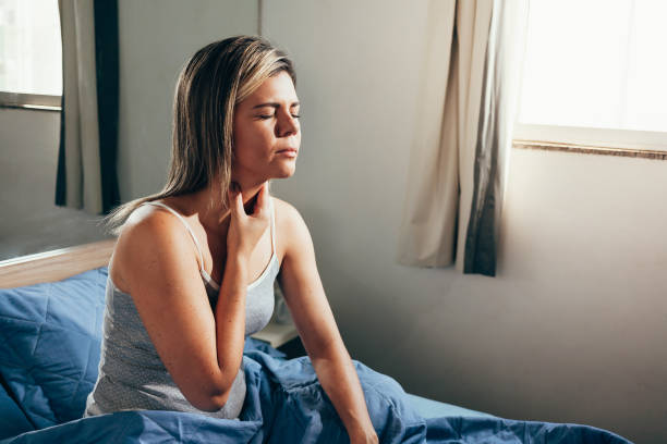 istock Young woman suffering from sore throat in bed 1129420721