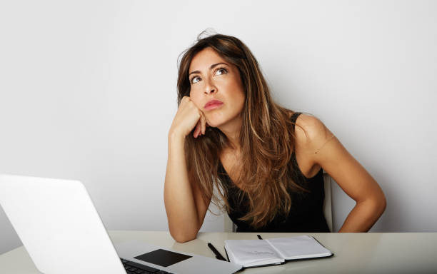istock Tired beautiful young woman dreaming over empty white background. Laptop and note pad on the table. Horizontal. 1129422062