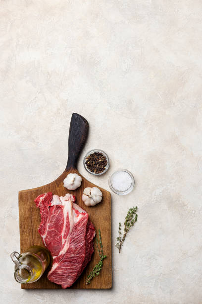 istock Beef meat with spices and garlic at wood board on white background 1129427604