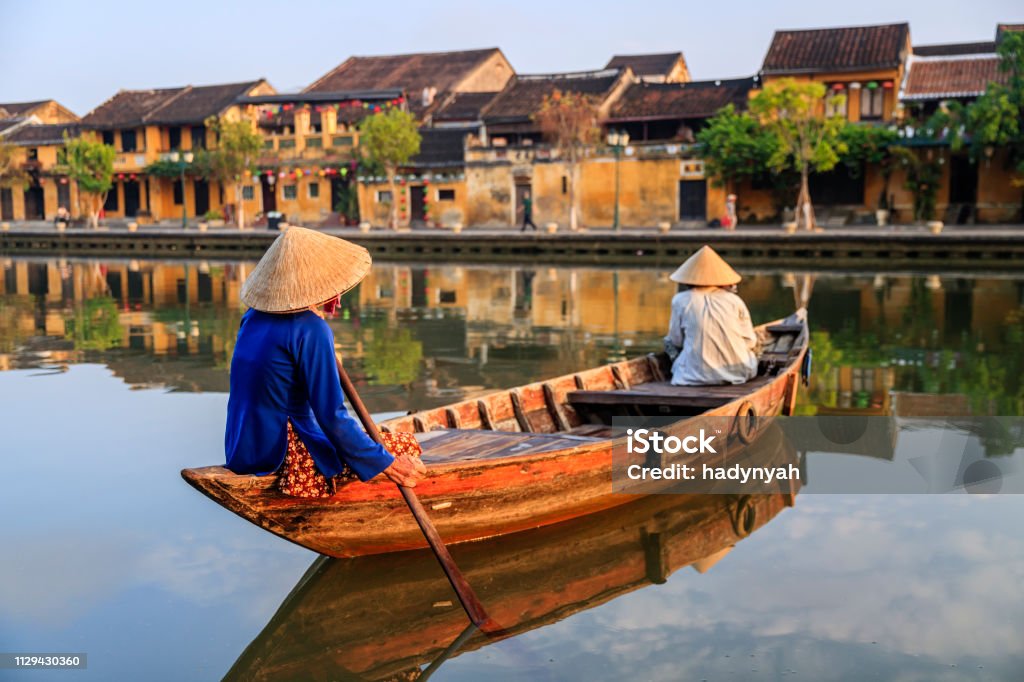 Vietnamese women paddling in old town in Hoi An city, Vietnam Vietnamese women paddling in old town in Hoi An city, Vietnam. Hoi An is situated on the east coast of Vietnam. Its old town is a UNESCO World Heritage Site because of its historical buildings. Vietnam Stock Photo