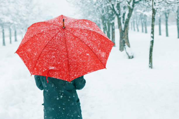 istock Woman with red umbrella in snow 1129432394