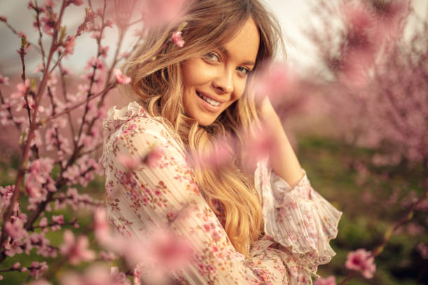 удивительная молодая женщина позирует в саду абрикосового дерева весной - манекенщица стоковые фото и изображения