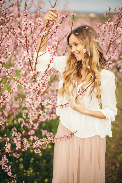 istock Amazing young woman posing in apricot tree orchard at spring 1129436441