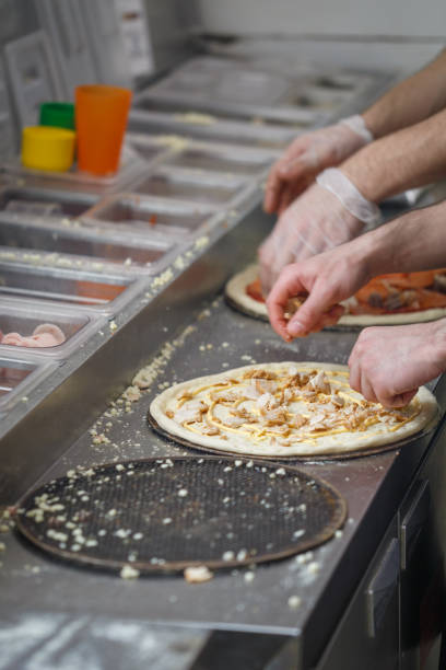 istock Baker lays chicken meat on the pizza base spread by mayonnaise 1129438846