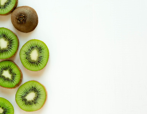 Stock photo showing a close-up view of healthy eating image of a group of Chinese gooseberry (kiwi), one cut in half displaying bright green flesh with ring of black seeds.