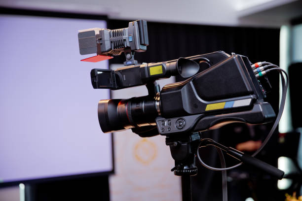 istock Camera recording publicity event . Press conference. Filming an event with a video camera.Professional digital Mirrorless camera with microphone on the tripod recording video - Image 1129451191