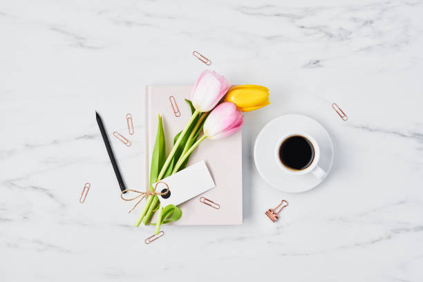 istock Office desk with coffee cup, tulips and pink diary 1129452038