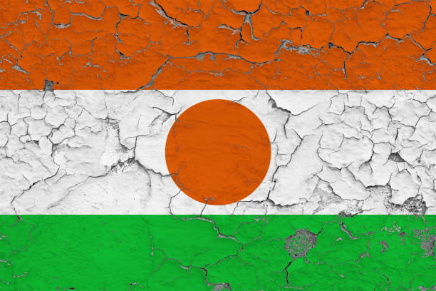 Flag of Niger painted on cracked dirty wall. National pattern on vintage style surface.