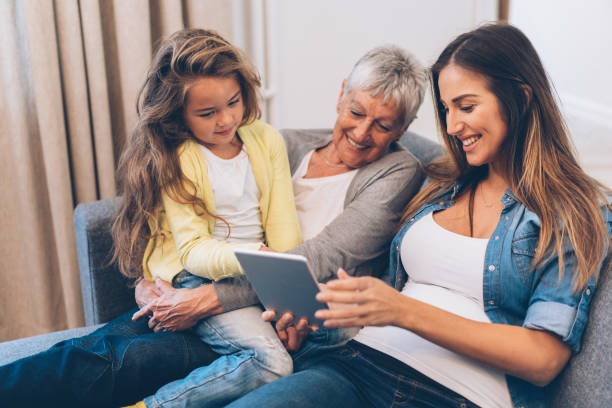 three generation women have fun at home - wireless technology cheerful granddaughter grandmother imagens e fotografias de stock