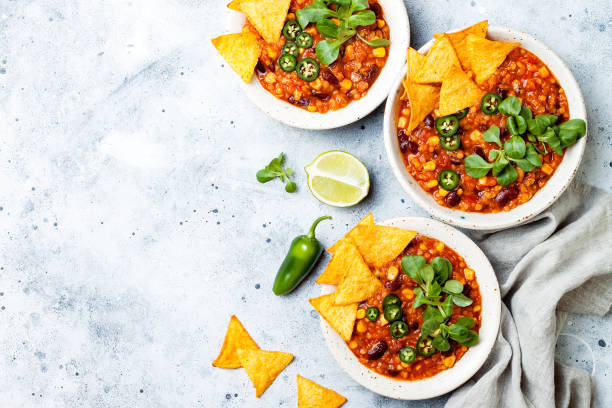 Vegetarian chili con carne with lentils, beans, nachos, lime, jalapeno. Mexican traditional dish stock photo
