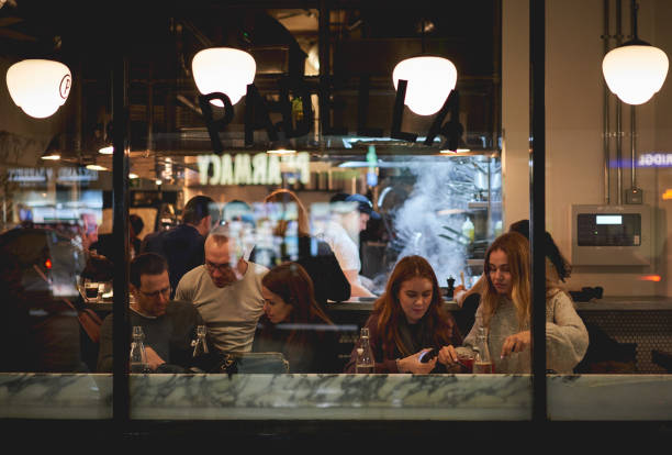Young people in a restaurant  in Borough market near London Bridge. London, UK - February, 2019. Young people in a restaurant  in Borough market near London Bridge. restaurant window stock pictures, royalty-free photos & images