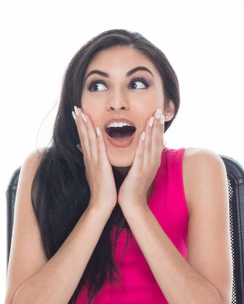 istock Beautiful latino female sitting at a white desk is feeling surprised 1129457457