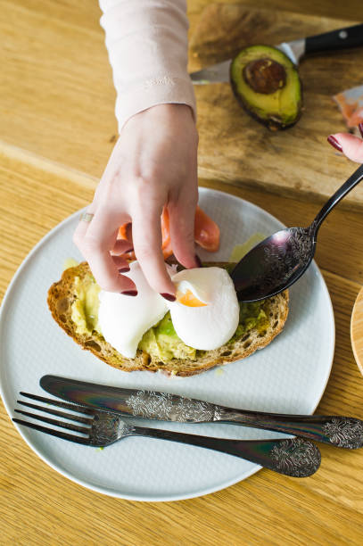 istock The chef lays an egg on toast with avacado and salmon on black bread. Side view, 1129461564