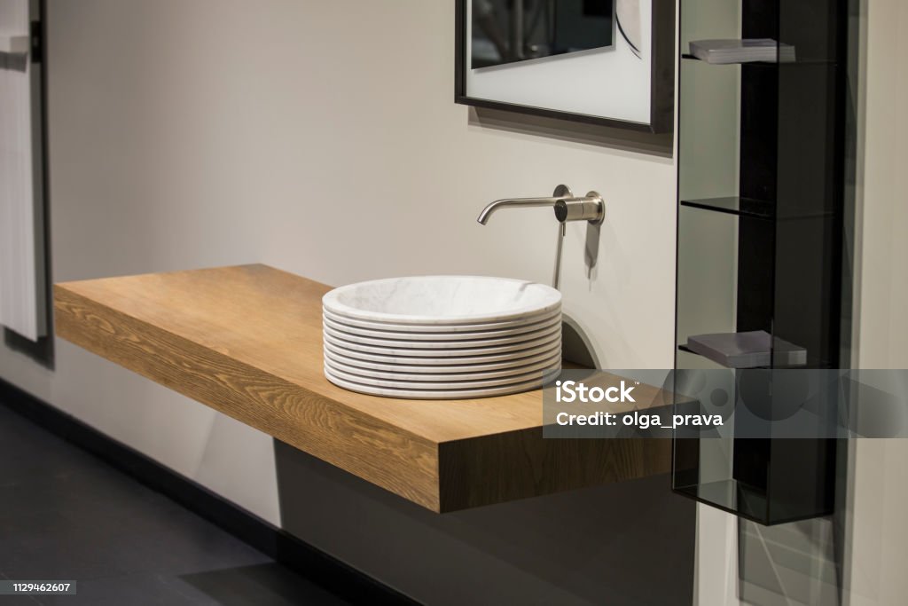 Modern gray and beige bathroom with wooden cabinet, round basin and mirror Modern gray and beige bathroom with wooden cabinet, round basin and mirror. Bathroom Stock Photo