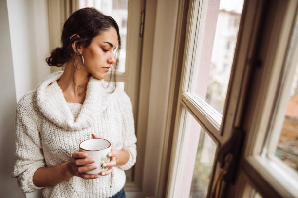 istock pensive woman in front of the window 1129464168
