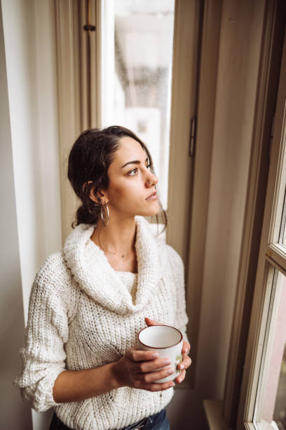 istock pensive woman in front of the window 1129464209
