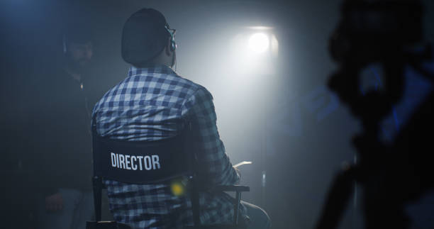 director sitting in his chair on a film set - dirigindo imagens e fotografias de stock